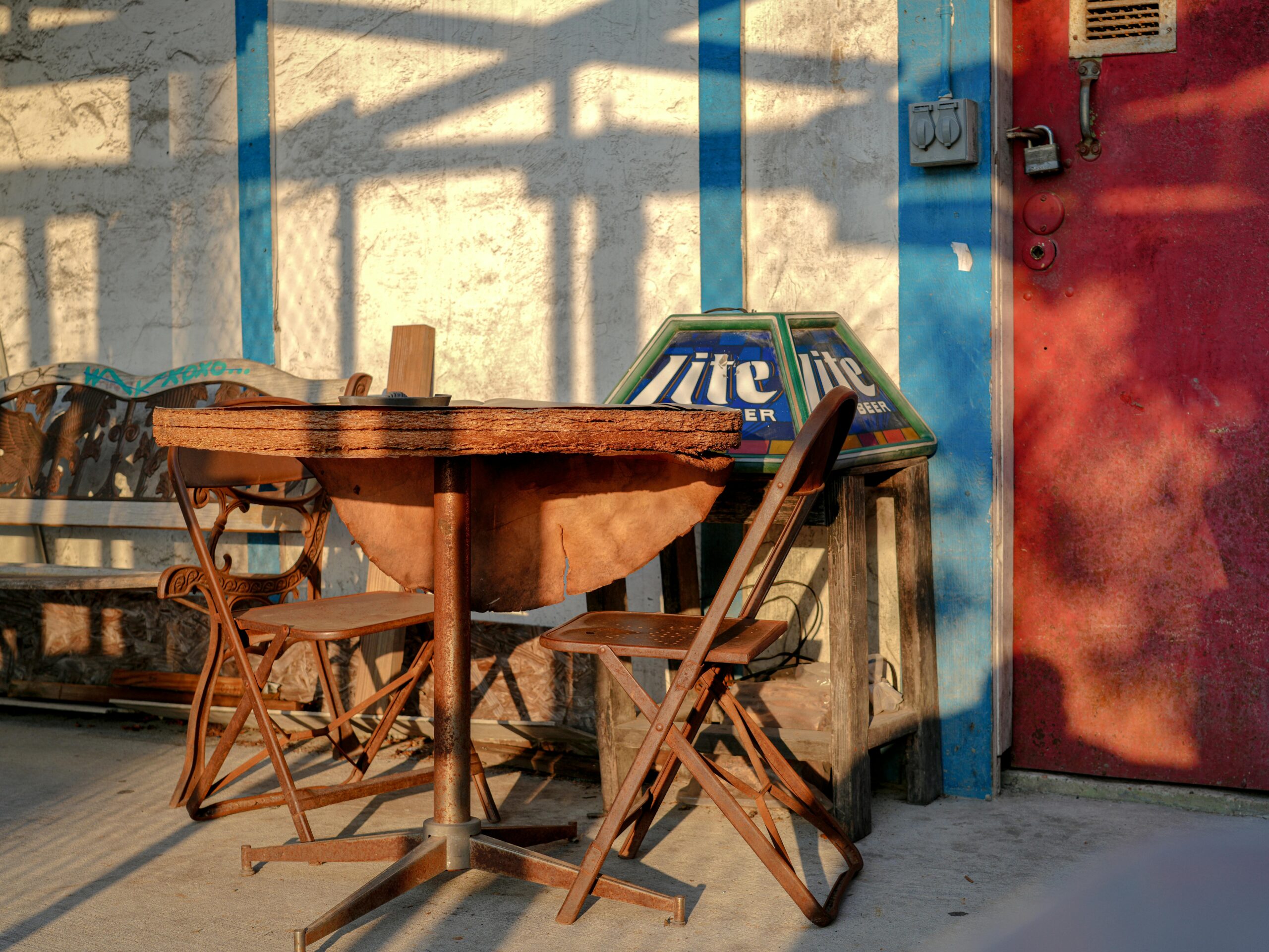 Warmes Abendlicht wirft Schatten auf eine rustikale Terrasse mit Sitzgelegenheiten und schafft eine einladende Bar-AtmosphÃ¤re.