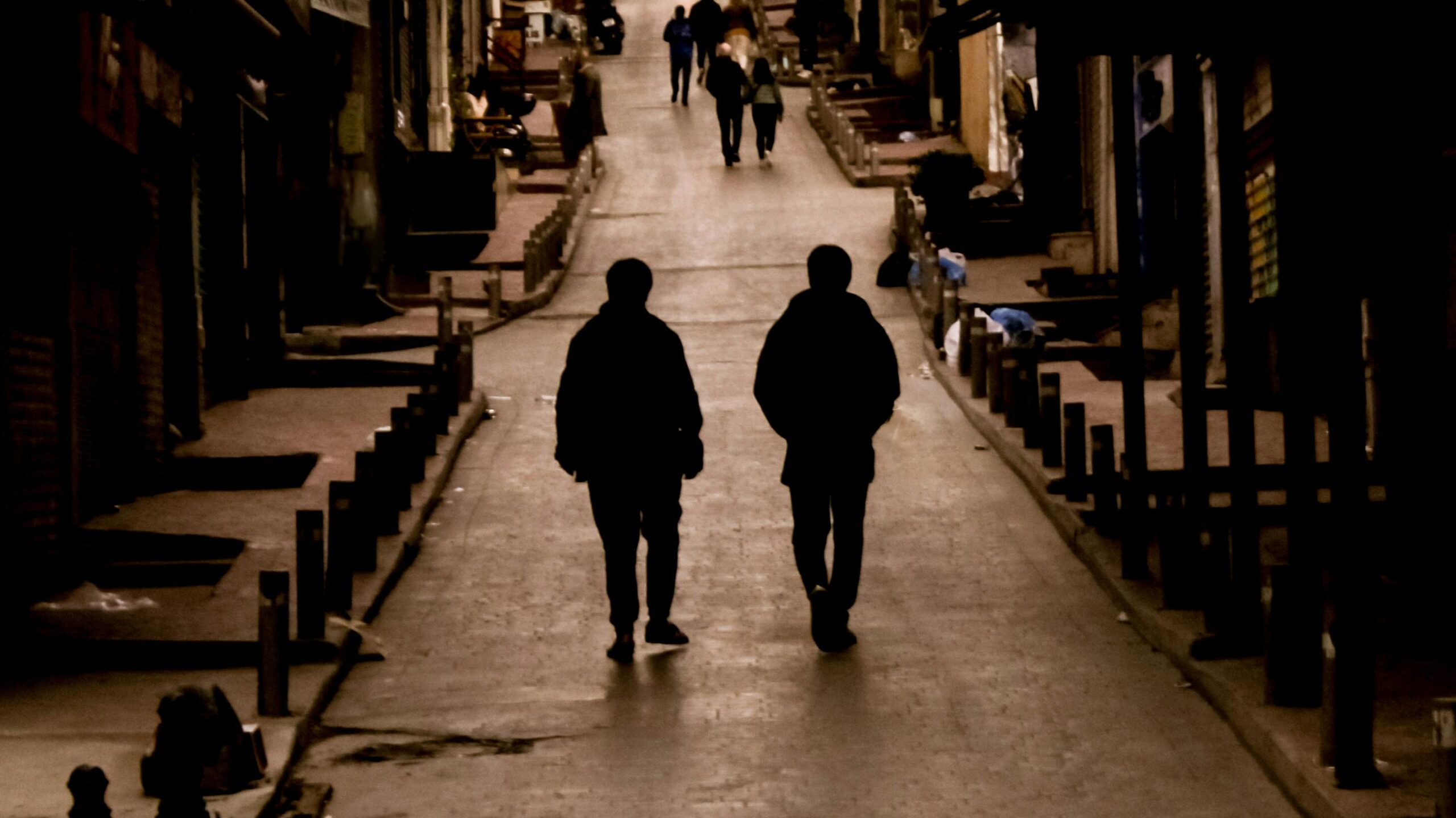 Zwei Silhouetten laufen durch eine schwach beleuchtete StraÃŸe in Istanbul und schaffen eine stimmungsvolle urbane Szene.