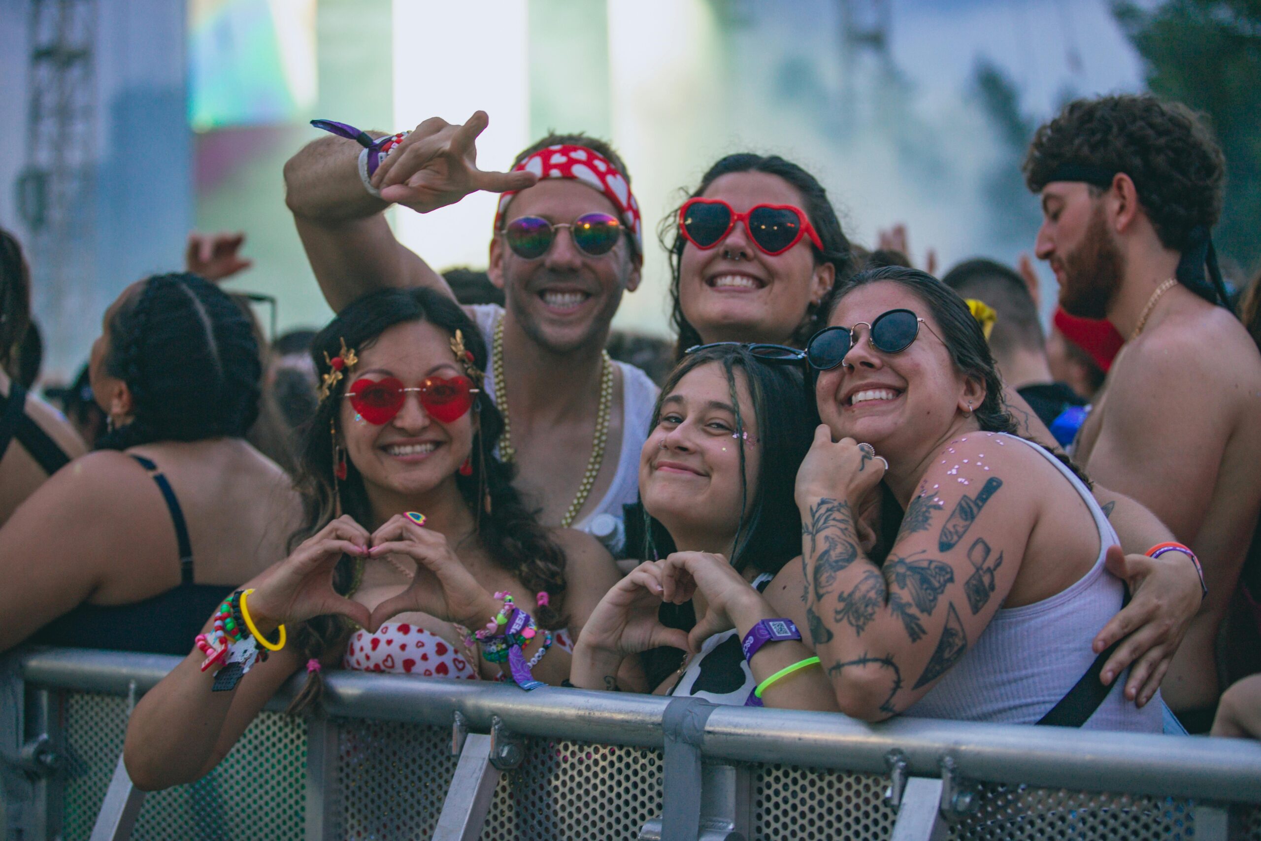 FrÃ¶hliche Gruppe von Freunden mit bunten Accessoires und Tattoos genieÃŸt ein Musikfestival im Freien.