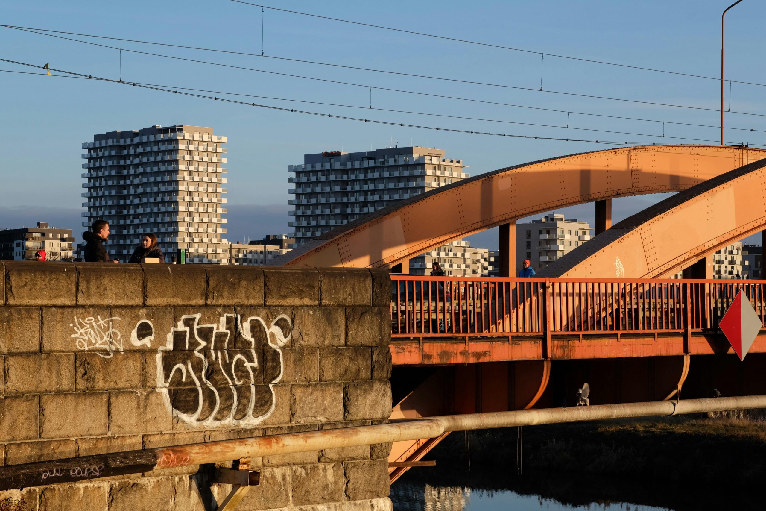 Stadtansicht mit einer BrÃ¼cke mit Graffiti und HochhÃ¤usern im Hintergrund.